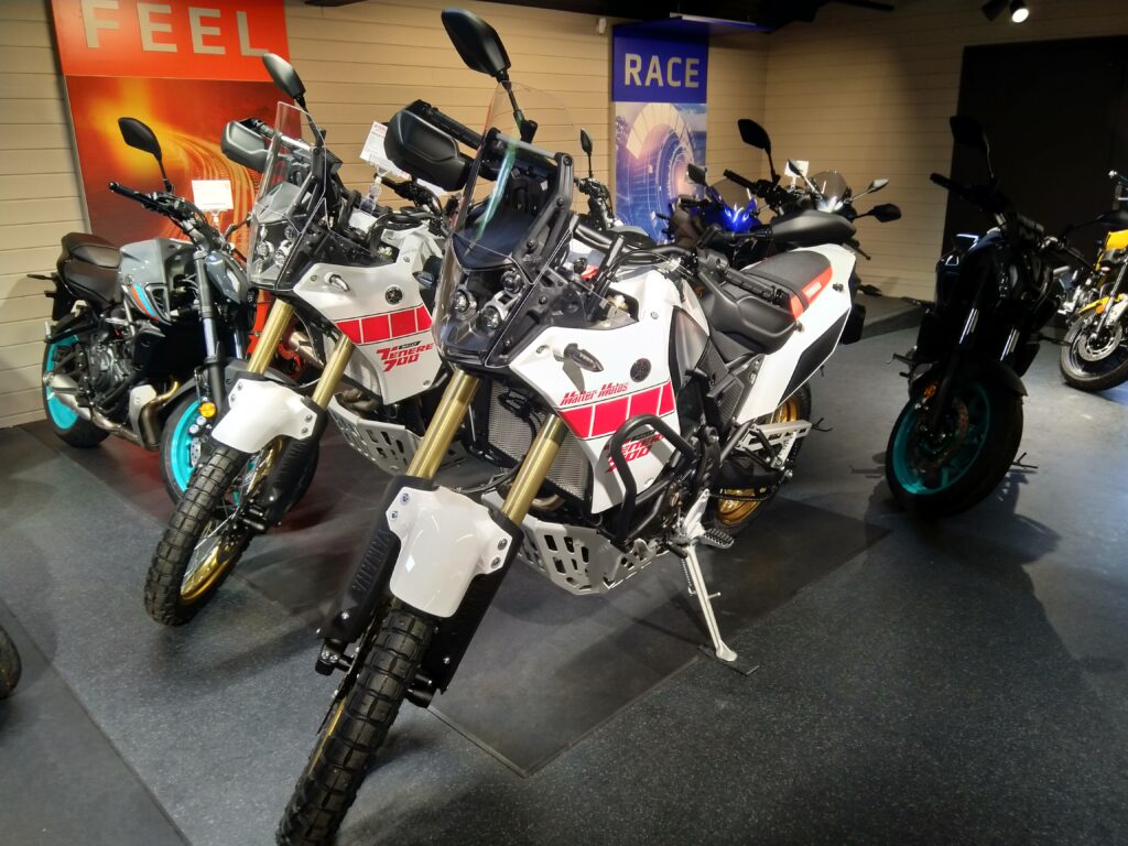 Mehrere Yamaha Ténéré 700 Modelle in der Motorrad-Ausstellung von Matter Motos: Highlight ist die neue Ténéré 700 World Raid 2026 in weiß-rot mit goldenen Felgen, goldener Upside-Down-Gabel, Rally-Scheibe und Offroad-Reifen. Daneben weitere Ténéré-Varianten und Modelle wie MT-Serie – professionell präsentiert in unserer Yamaha Fachwerkstatt.